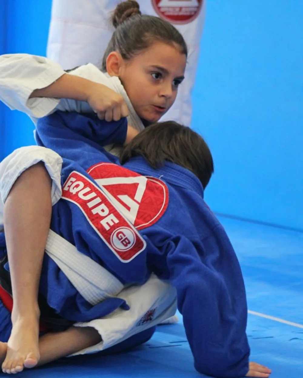 Kids training with a coach on the mat at Gracie Barra Coppell